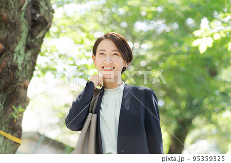 緑道を歩くスーツの女性 95359325