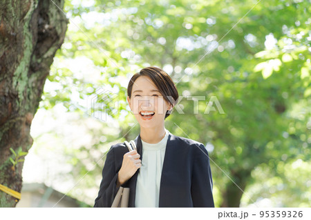 緑道を歩くスーツの女性 95359326