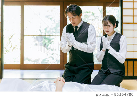 仏衣を着せて合掌する葬儀スタッフ（納棺師） 95364780
