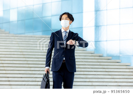 オフィスのロビーで立つスーツ姿の若いビジネスマン 95365650