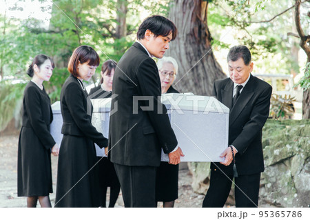 お葬式で棺桶を霊柩車に運ぶ遺族 95365786