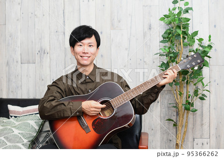 屋内でギターを弾く男性 95366262