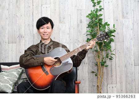 屋内でギターを弾く男性 屋内でギターを弾く男性 95366263