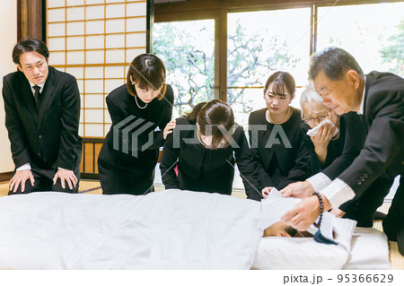 お葬式・お通夜で布団を囲み故人を弔う遺族（泣く） 95366629