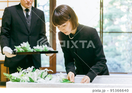 お葬式の納棺で花入れの儀をする日本人女性 お葬式の納棺で花入れの儀をする日本人女性 95366640
