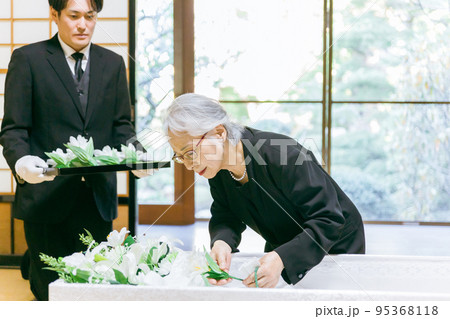 お葬式の納棺式で花入れの儀をする高齢者女性 95368118