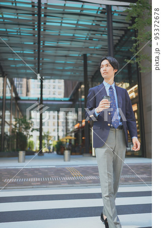 ビジネス街をコーヒーを持って歩くビジネスマン	 95372678