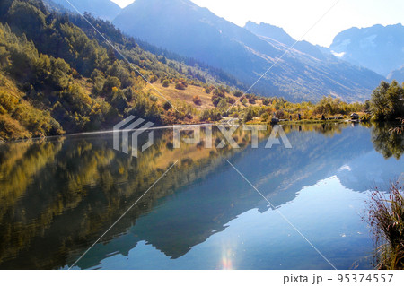 Majestic view of the mountains reflected in the lake in the morning haze. Merging with nature, environmental friendliness, ecology. Abstract natural background. Wallpaper. 95374557