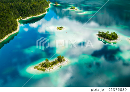 Unique islands with trees on a lake, turquoise water and clouds reflect, aerial view. Unique islands with trees on a lake, turquoise water and clouds reflect, aerial view. 95376889