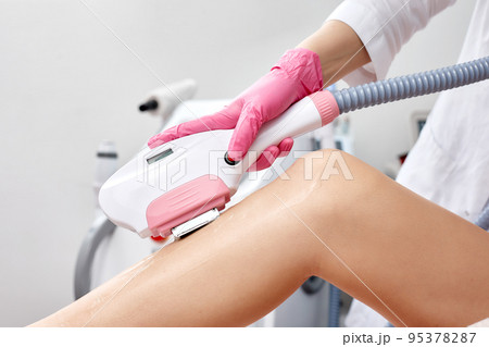 Laser depilation or photoepilator process on a woman leg. 95378287