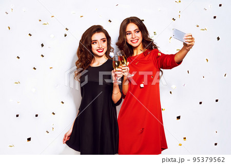 portrait of two happy young women who make selfie. in evening dresses on party over white background. 95379562