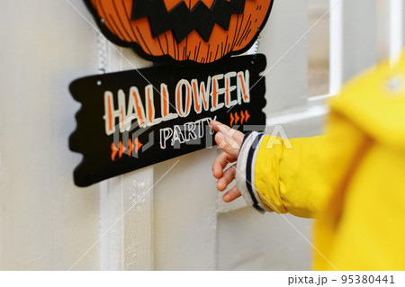 A kid with Carved pumpkin hanging on the fence of the house A kid with Carved pumpkin hanging on the fence of the house 95380441