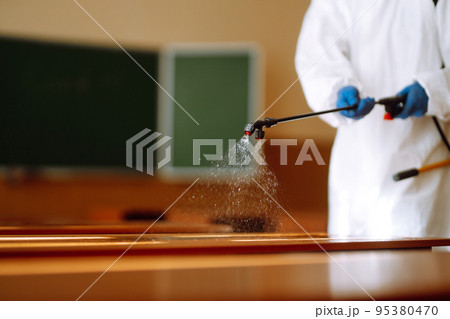 Disinfectant sprayer in the hand of man in protective hazmat suit. Disinfecting schools during coronavirus. 95380470