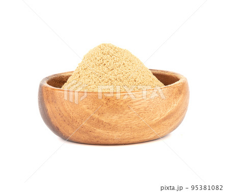 Wooden bowl with ground ginger root powder on a white background. 95381082