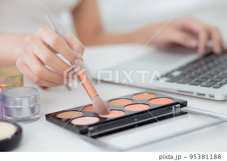 Hands of woman with learning makeup with brush on cheek on laptop computer with tutorial course. 95381188