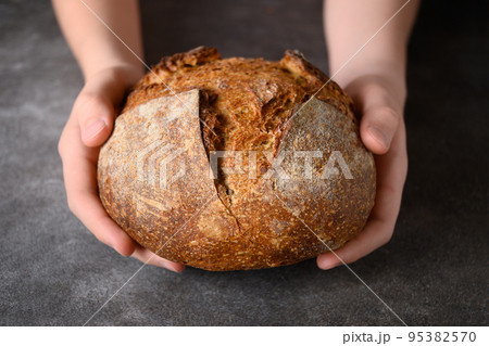 Loaf of freshly baked bread in hands. Loaf of freshly baked bread in hands. 95382570