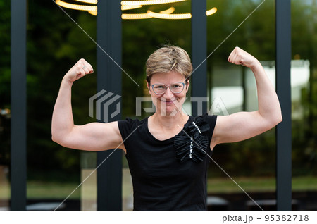 Portrait of a short haired white 35 yo woman showing her strong arms Portrait of a short haired white 35 yo woman showing her strong arms 95382718