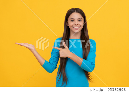 happy child with long hair presenting product and point finger on copy space, advertisement. 95382998