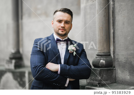 Happy handsome smiling groom posing with boutonniere Happy handsome smiling groom posing with boutonniere 95383929
