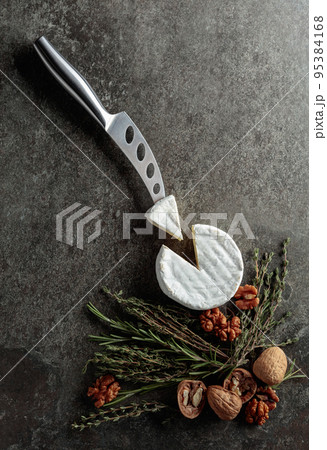 Brie cheese with walnuts, thyme, and rosemary on an old stone background. Brie cheese with walnuts, thyme, and rosemary on an old stone background. 95384168