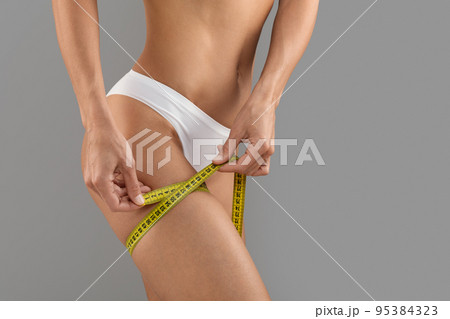 Body Sculpting. Unrecognizable Young Woman In Underwear Measuring Thigh Size With Tape Body Sculpting. Unrecognizable Young Woman In Underwear Measuring Thigh Size With Tape 95384323