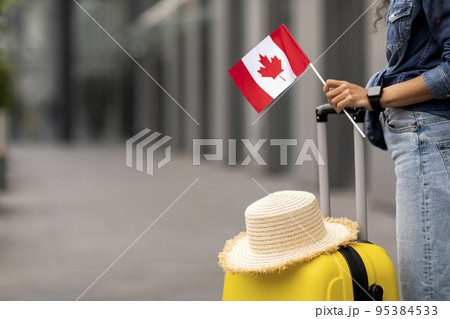 Cropped of woman traveller holding flag of Canada, going abroad 95384533