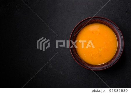 Delicious hot pumpkin and carrot soup puree with spices and herbs Delicious hot pumpkin and carrot soup puree with spices and herbs 95385680
