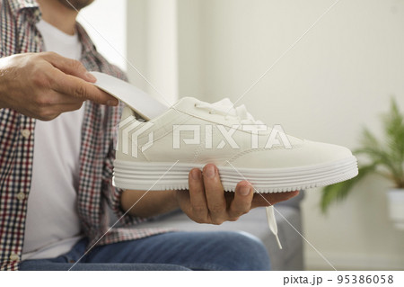 Young man puts new orthotic insoles inside his comfortable white orthopedic shoes 95386058