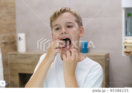 Close up head shot mirror reflection of a happy boy flossing his teeth. Close up head shot mirror reflection of a happy boy flossing his teeth. 95386155