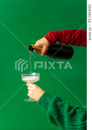 Festive background concept for Christmas party, hand pouring champagne, wine into glass Festive background concept for Christmas party, hand pouring champagne, wine into glass 95386600