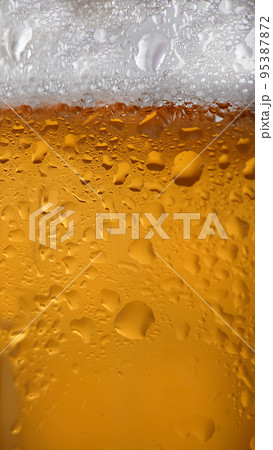 Liquid drops on a foamy beer glass close-up Liquid drops on a foamy beer glass close-up 95387872