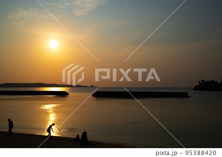 沖縄の夕陽と海、人のシルエット 95388420
