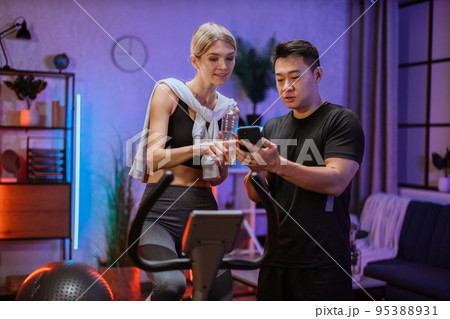 Portrait of female wearing sport bra holding bottle water working out using exercise bike 95388931
