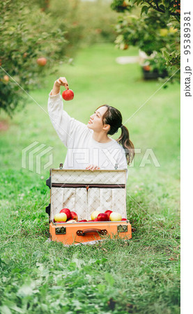 トランクいっぱいのりんごと白いTシャツの女性 95389381