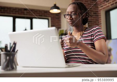 Remote student speaking on online meeting, woman working on laptop in home office. Employee attending virtual meeting, young freelancer in glasses talking on teleconference Remote student speaking on online meeting, woman working on laptop in home office. Employee attending virtual meeting, young freelancer in glasses talking on teleconference 95389995