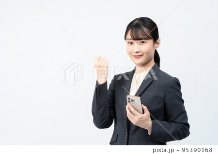 スマホを持つスーツの女性（白バック、ガッツポーズ） 95390168