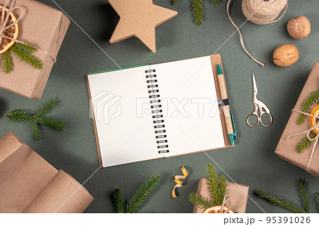 Winter holiday mockup. Blank white notepad, boxes, craft paper, twine and natural decor for wrapping XMAS, New Year gifts on green background. Concept Zero waste Merry Christmas Mockup Winter holiday mockup. Blank white notepad, boxes, craft paper, twine and natural decor for wrapping XMAS, New Year gifts on green background. Concept Zero waste Merry Christmas Mockup 95391026