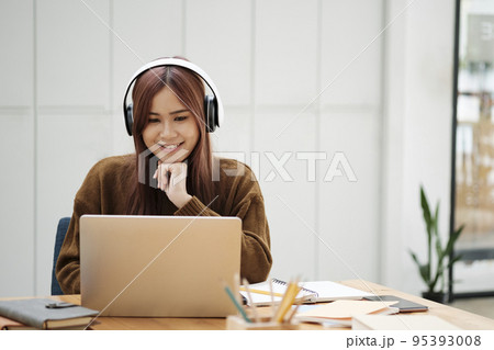 Young woman studying or working online using laptop and wearing headphones. Young woman studying or working online using laptop and wearing headphones. 95393008