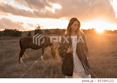 A girl in a white airy dress stands next to a horse and poses in the forest at sunset, like in a fairy tale. Well-groomed face with beautiful cosmetics. Enjoy nature and animals. Horse riding in the A girl in a white airy dress stands next to a horse and poses in the forest at sunset, like in a fairy tale. Well-groomed face with beautiful cosmetics. Enjoy nature and animals. Horse riding in the 95394122