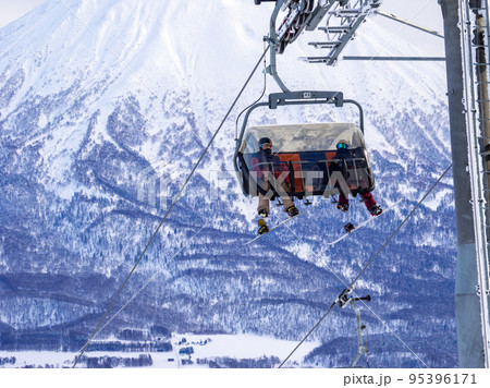 羊蹄山を背景にリフトに乗るスノーボーダー (北海道、ニセコ) 95396171