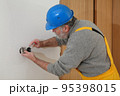Electrician at construction site install electrical plug 95398015