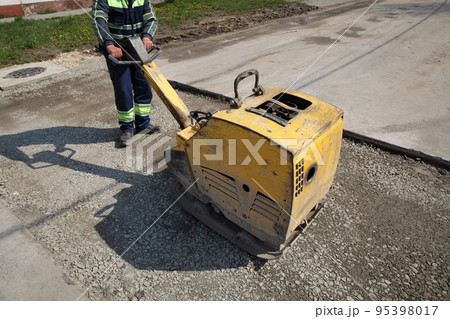Worker use vibratory plate compactor at road construction site Worker use vibratory plate compactor at road construction site 95398017