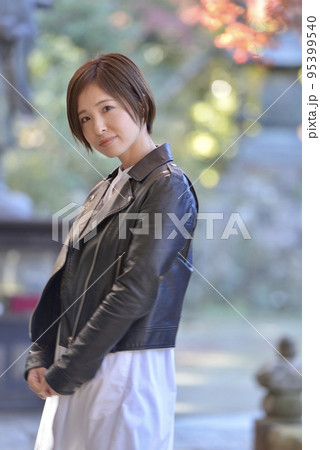 紅葉を背景にポーズをとるショートヘアの微笑む若い女性 95399540