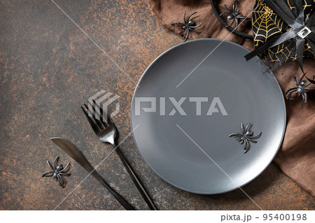 Top view of blank halloween plate on a stone table. Halloween table setting with cutlery. Festive concept. 95400198