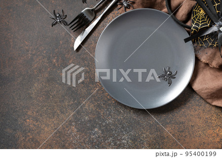 Top view of blank halloween plate on a stone table. Halloween table setting with cutlery. Festive concept. Top view of blank halloween plate on a stone table. Halloween table setting with cutlery. Festive concept. 95400199