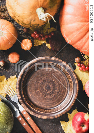 Thanksgiving day concept. Autumn table setting for dinner with plate, knife, fork decorated pumpkins and maple leaves. Flat lay autumn composition. Thanksgiving day concept. Autumn table setting for dinner with plate, knife, fork decorated pumpkins and maple leaves. Flat lay autumn composition. 95400213