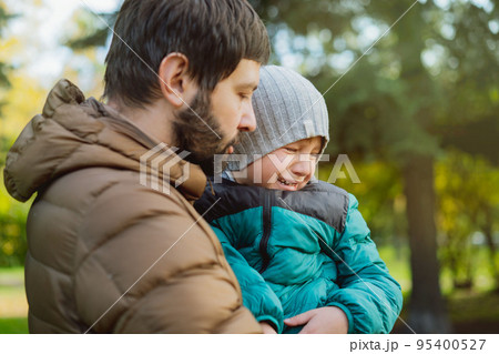 Young caucasian man, dad of little boy pacifying his crying son, hugging him. Father's day concept. 95400527