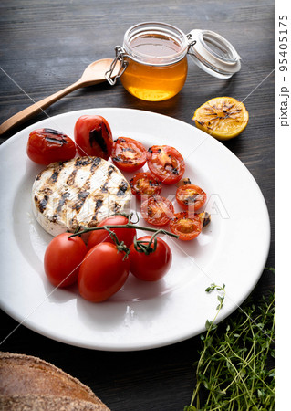 Camembert cheese is round, grilled, poured with golden honey on a wooden cutting board. Soft selective focus, black background.Space for copying. Healthy eating. Vertical photo. Camembert cheese is round, grilled, poured with golden honey on a wooden cutting board. Soft selective focus, black background.Space for copying. Healthy eating. Vertical photo. 95405175