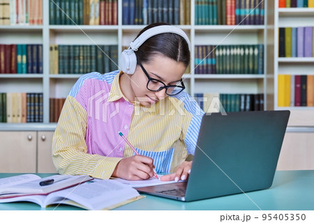 Teenage girl student studying in library, using laptop Teenage girl student studying in library, using laptop 95405350