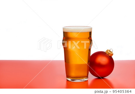 Pint glass of ale or beer with christmas bauble on red background Pint glass of ale or beer with christmas bauble on red background 95405364